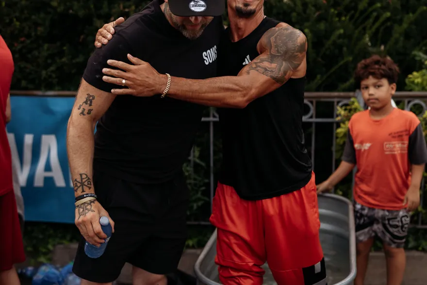 Two men embracing and laughing together after a baptism.